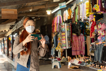 Wall Mural - Hipster woman traveler with mask and backpack taking photo by mobile in ayothaya thailand, Travel Holiday Relaxation Concept