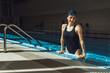 © Dzmitry - Portrait of smiling athletic female swimmer in professional swimsuit cap and glasses leaning on edge of swimming pool and looking at camera during training