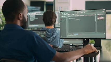 African american system engineer working on software development with source code, looking at computer. IT app developer writing ai algorithm in office, online cloud computing. Handheld shot.
