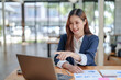 © amnaj - Portrait of smiling Asian business woman enjoying work ideas sitting on laptop at office.