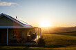 © Austockphoto - Homestead on hilltop with last rays of sunlight shining over scene and solar panels on roof