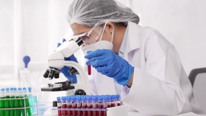 Wall Mural - Doctor hand taking a blood sample tube from a rack with machines of analysis in the lab background, Technician holding blood tube test in the research laboratory.