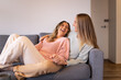© Austockphoto - Laughing female same sex couple  in the living room, cuddling on the grey sofa