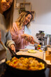 © Austockphoto - Two women laughing as they cook together at home