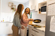 © Austockphoto - Happy female same sex couple cooking together and being affectionate in the kitchen