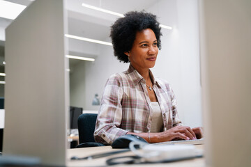 Concentrated black businesswoman employee worker analyzing online sales statistics data on computer