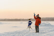 Kid in warm winter outfit playing in snow with dog on beautiful brumal day
