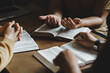 © Deemerwha studio - Christian group of people holding hands praying worship together to believe and Bible on a wooden table for devotional for prayer meeting concept.