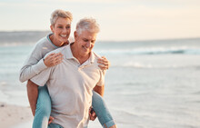 Love, Beach And Piggyback With A Senior Couple Walking By The Sea Or Ocean While On A Date In Summer Together. Nature, Earth And Water With An Elderly Man And Woman Pensioner Taking A Walk On A Coast