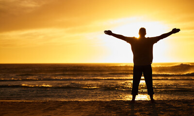 silhouette of man with view, sunset and beach with arms out by the ocean, carefree and peace, freedo