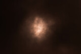 Fototapeta  - Niebo pokryte grubą warstwą ciemnych, złowrogich, burzowych chmur. W środkowej części poprzez cieńszą warstwę chmur przebija się zabarwione na czerwono światło.