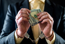 Composition Of The Hands Of A Business Man With Money In His Hands And Handcuffs On Them.
