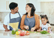 © J Maas/peopleimages.com - Cooking, kitchen and family with a girl, mother and father preparing food for a meal in their home together. Children, health and diet with a man, woman and daughter making dinner in a house