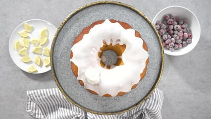 Poster - Time lapse. Flat lay. Step by step. Decorating lemon cranberry bundt cake with sugar cranberries and lemon wedges on a cake stand.