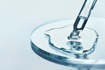 pipette with sample of cosmetic product in petri dish on blue background, selective focus