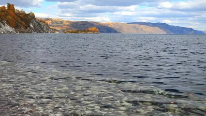 Wall Mural - autumn landscape with clear water of baikal lake and yellowed trees on coastal rocks. view of natura