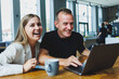 © DSMT - Young colleagues managers are sitting at the table and laughing. Concept of business cooperation and teamwork. Young smiling people at the table in the office with a laptop. Modern successful people