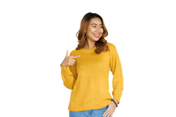 Sticker - Attractive positive young asian brunette woman in yellow sweater on white background. Hands pointing