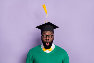 Wall Mural - Portrait of impressed excited man student graduate university receive diploma isolated on purple color background