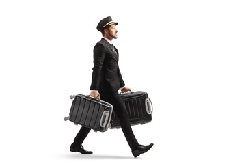 Wall Mural - Full length profile shot of a bellboy walking and carrying two suitcases