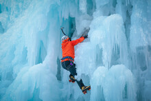 Alpinist Man With Ice Climbing Equipment On A Frozen Waterfall