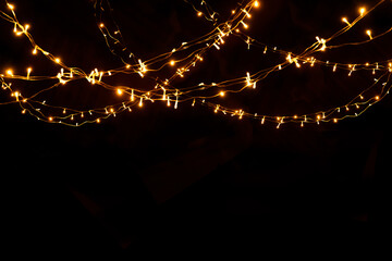 Abstract Christmas lights on black background. Glowing light bulb garland,