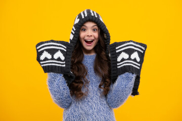 Warm hat with hood and scarf. Amazed teenager. Modern teenage girl 12, 13, 14 year old wearing sweater and knitted hat on isolated yellow background. Excited teen girl.
