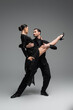 © LIGHTFIELD STUDIOS - Professional dancers looking at each other while performing tango on grey background