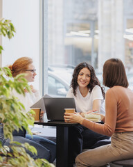 Wall Mural - three female friends or colleagues are working and doing brainstorming. students or business partners in coworking create a project. young successful women entrepreneurs and designers. small business