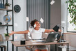 © standret - Paper is in the air. Passes the exam. Cute female african american student child is sitting by the laptop