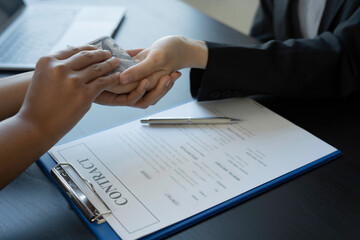 Wall Mural - The client hands the money to the Asian female agent, a fictitious agent in an agreement to sell the house in the office.