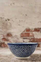 Wall Mural - Blue porcelain bowl with white dots on a gray brick background