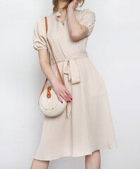 Studio shot of woman in classy simple beige viscose summer dress.