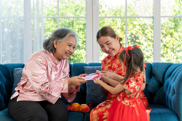 Wall Mural - Grandmother give red envelopes to her daughter and granddaughter