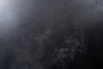 Fototapete - Dense Fluffy Puffs of White Smoke and Fog on black Background, Abstract Smoke Clouds, Movement Blurred out of focus. Smoking blows from machine dry ice fly fluttering in Air, effect texture