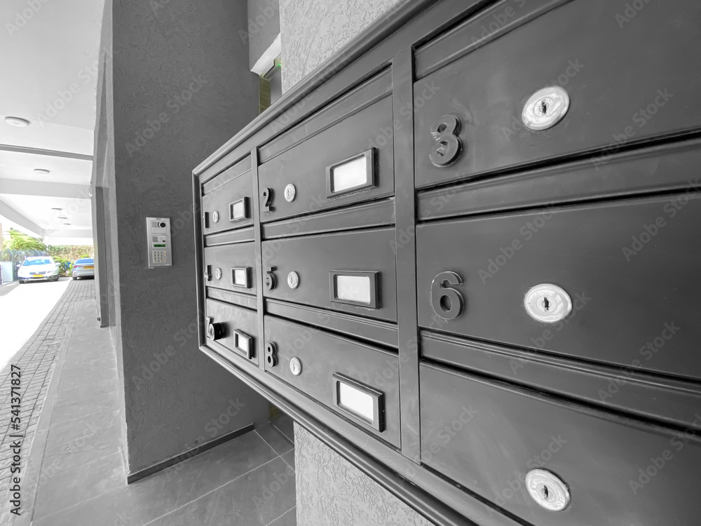 Closeup view of modern mailboxes on grey wall in residential building