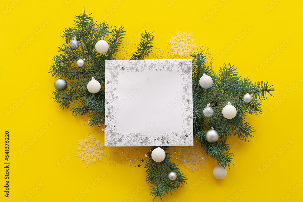 Blank card with Christmas balls and fir branches on yellow background
