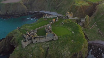 Sticker - Aerial shot of the Dunnottar Castle on green mountains with the blue sea below