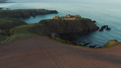 Poster - Aerial shot of the Dunnottar Castle on a mountain with the clear water below