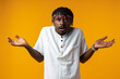 © fotofabrika - Young afrcian man on yellow background showing helpless gesture with hands