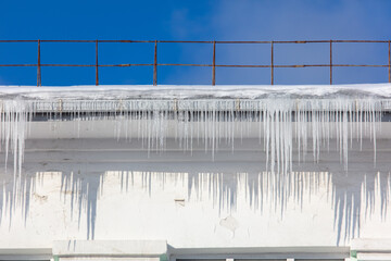 Wall Mural - Icicles hang from the roof of the house.