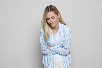 Wall Mural - Young woman suffering from menstrual pain on light grey background