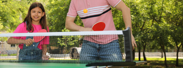 Wall Mural - Happy man with his daughter playing ping pong in park. Banner design