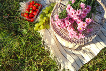 Picnic Basket, Flowers And Berries On Blanket Outdoors
