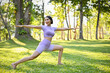 © bongkarn - Active and fit Asian woman posing warrior ii yoga pose, practicing yoga in the green park