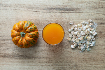 Wall Mural - Orange pumpkin, pumpkin seeds and a glass of pumpkin juice on a wooden background, pumpkin is a source of vitamins and antioxidants