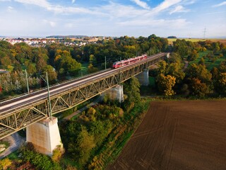 Sticker - Aerial view of train in motion on bridge surrounded by dense trees