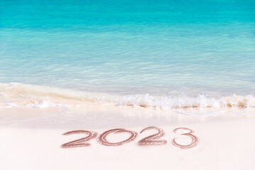 2023 written on the sand of a tropical beach, travel new year card