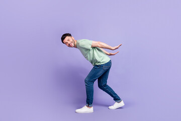 Full length photo of nice young man carry empty space back toothy smile dressed stylish gray garment isolated on purple color background