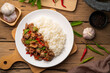 Stir-fried Chicken Giblets(livers, heart and gizzards) with Chillies and basil in white plate with cooked rice.top view